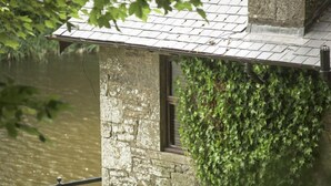 A stone building with a window and a metal railing overlooking a body of water. - Forbes of Kingennie Country Resort (Dundee)