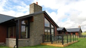 A modern building with large windows, a stone facade, and a wooden deck with chairs. - Forbes of Kingennie Country Resort (Dundee)