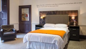 Una habitación de hotel con cama, mesitas de noche, una silla y una puerta.