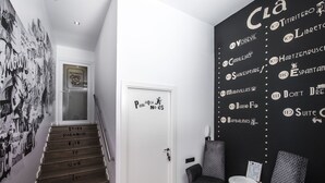 A staircase with a sign reading "Por aqui no es" leading to a door. There are two chairs and a small table against a wall with various names and numbers. - Clá Hotel Boutique (Teruel)