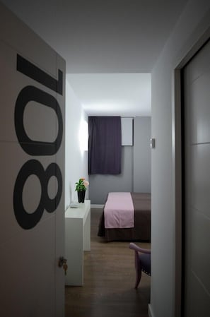 A modern hotel room with a minimalist design, featuring a bed, a small desk with a plant, and a large window with curtains. - Clá Hotel Boutique (Teruel)