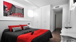 A bedroom with a bed, a nightstand, a white wardrobe, and a painting on the wall. - Clá Hotel Boutique (Teruel)
