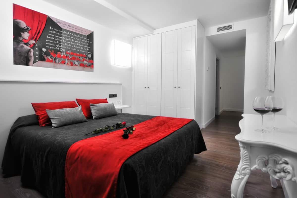 Un dormitorio con una cama, una mesita de noche, un armario blanco y un cuadro en la pared.