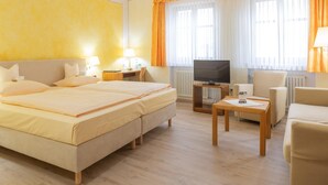 A hotel room with a large bed, a TV, a desk, and a chair.