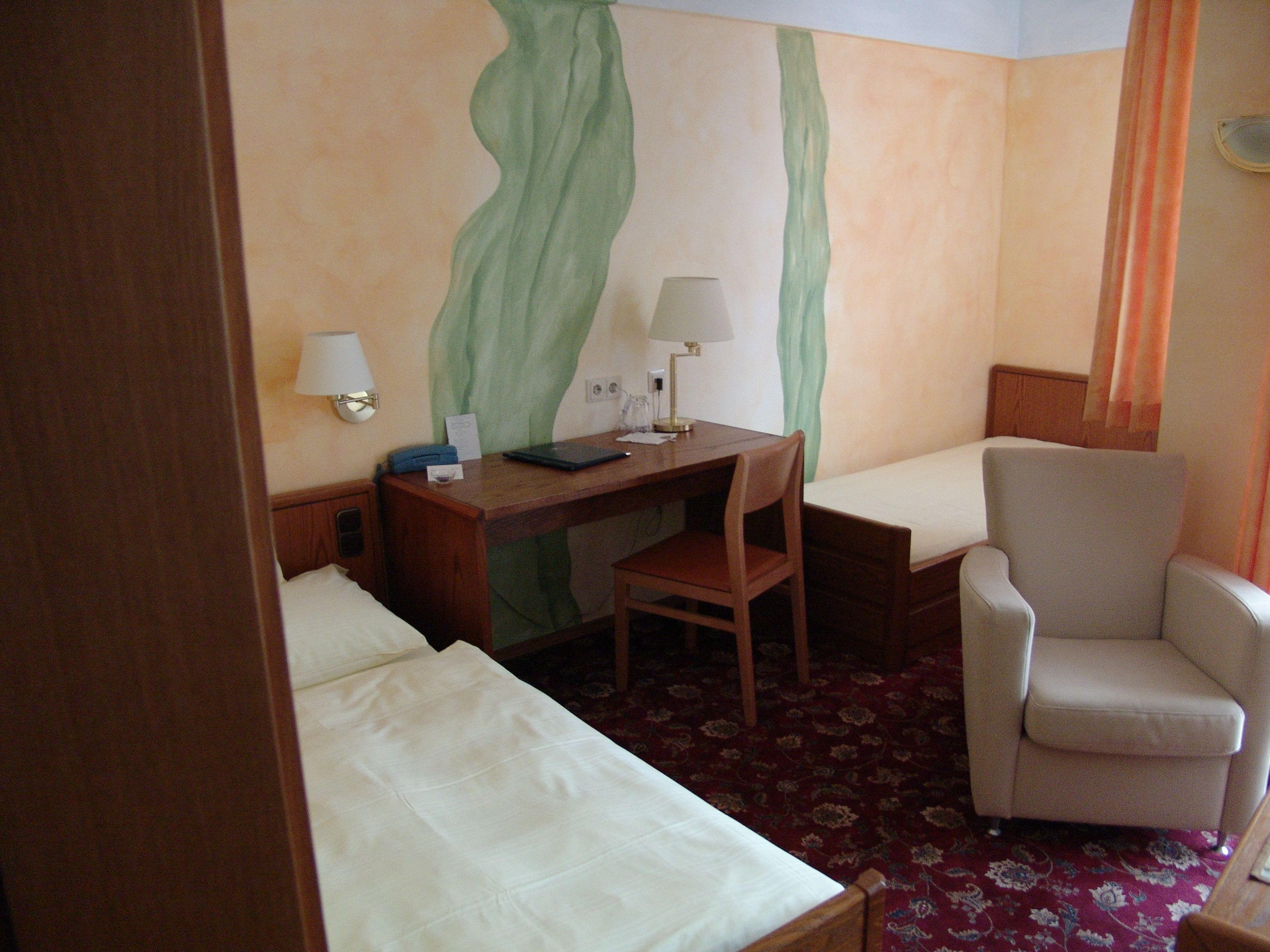 Una habitación de hotel con una cama, un escritorio con silla, una lámpara y un sofá.
