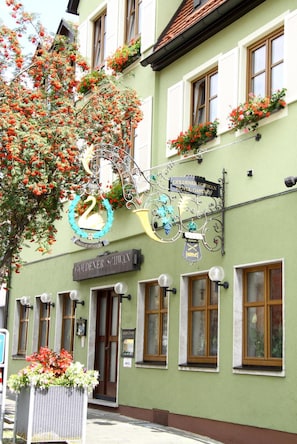 A hotel with a swan logo, flower boxes, and a sign reading "GOLDENER SCHWABN HOTEL GASTHOF".