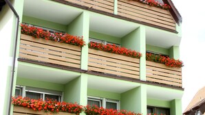 A multi-story building with balconies adorned with red flowers.