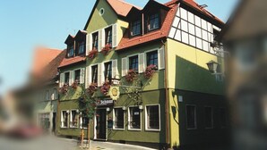 A traditional European building with a green facade, multiple windows, and a red-tiled roof.