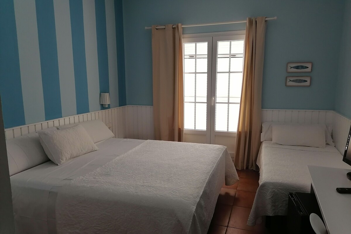 A hotel room with two beds, a window with curtains, a lamp, and a wall with a fish decoration.