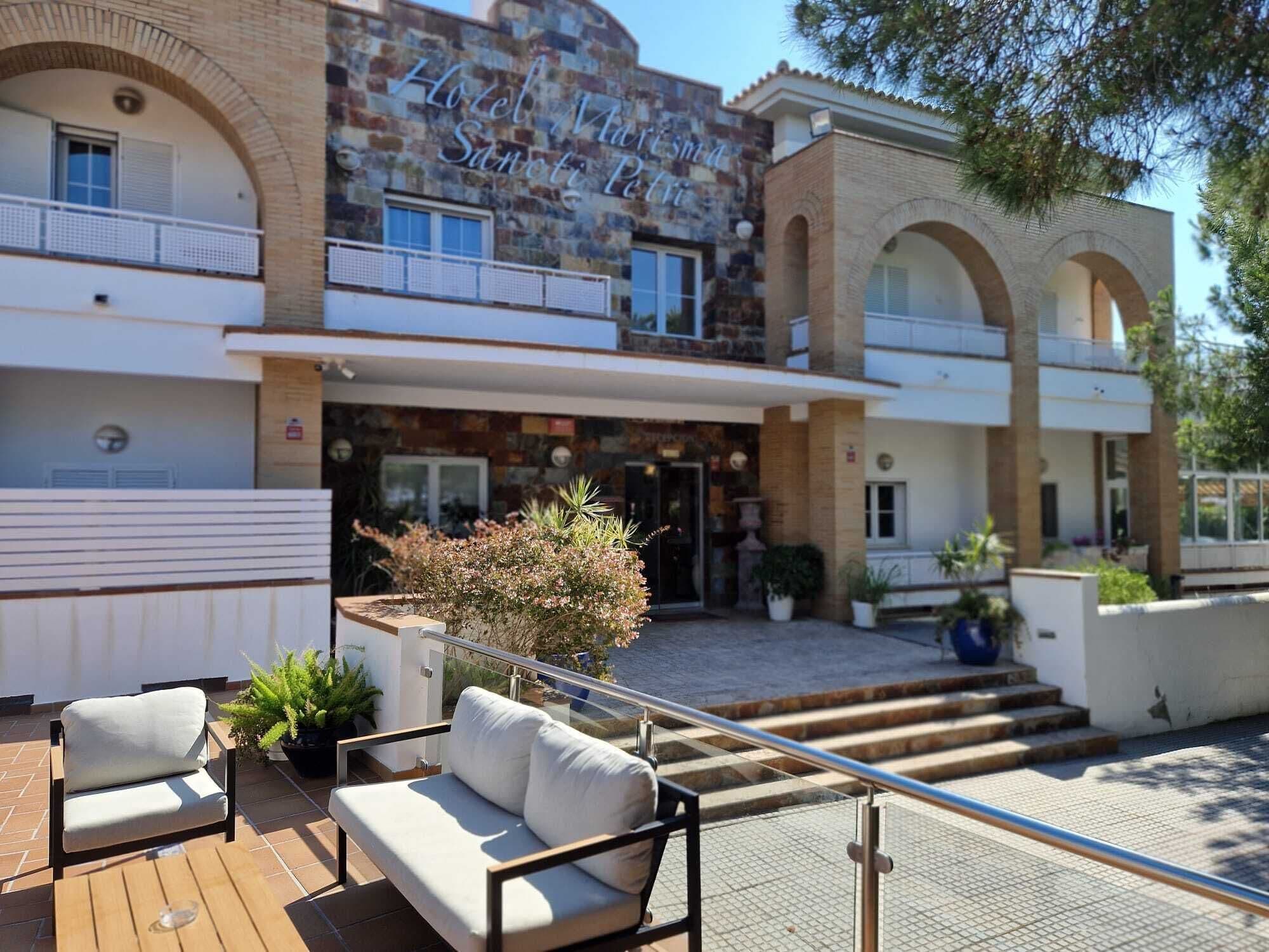 A hotel with a stone facade, outdoor seating area, and a staircase leading to the entrance.
