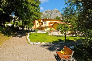 A building with a yellow facade, a paved pathway, and a bench with fruit. - Verdeblu House (San Giovanni a Piro)