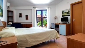 A hotel room with a bed, a desk with a computer, a TV, a chair, a wardrobe, and a window with curtains. - Verdeblu House (San Giovanni a Piro)