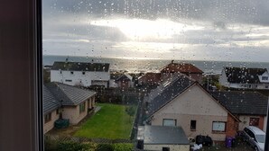 A residential area with houses, a grassy yard, and a body of water in the background. - Seaview Guest House (Carnoustie)