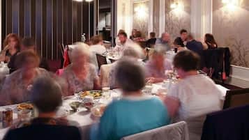 Zona pranzo con diversi tavoli, sedie e un televisore montato a parete.