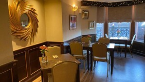 A dining area with a round mirror, wooden paneling, and a view of the outside balcony. - The Station Hotel (Carnoustie)