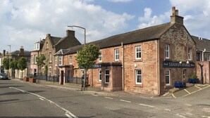 A traditional brick building with a sign for a hotel and a food station. - The Station Hotel (Carnoustie)