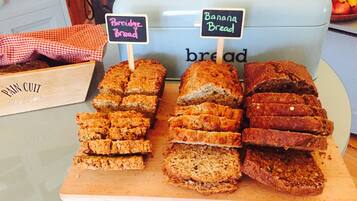 Eine Auswahl an Brotscheiben mit Schildern, auf denen 'Porridge Bread' und 'Banana Bread' in einer Bäckerei stehen.
