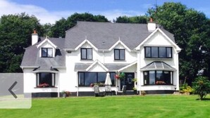 A large, two-story house with a well-maintained lawn in front. - Railway Country House B&B (Gorey)