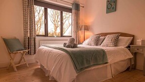 A bedroom with a bed, a chair, a lamp, and a window with curtains. - Railway Country House B&B (Gorey)