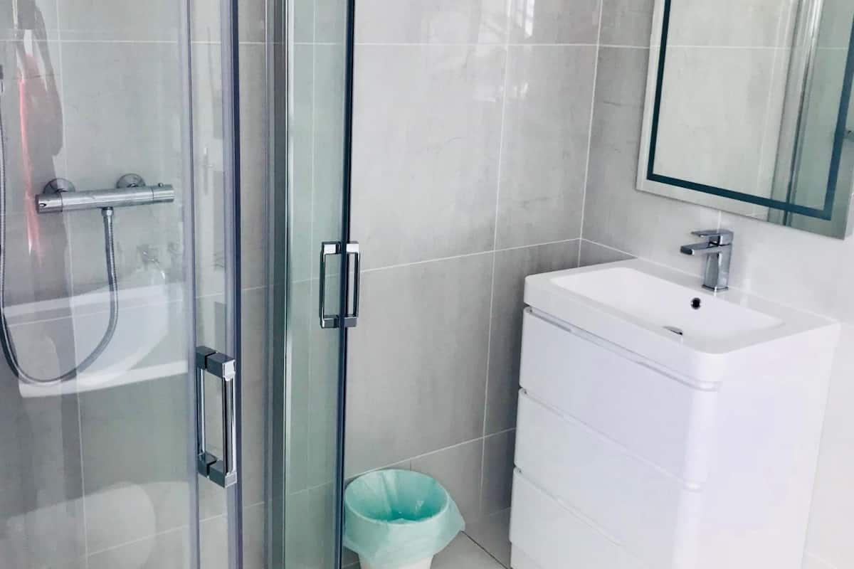 A modern bathroom with a glass shower enclosure, a white sink, and a mirror above the sink.
