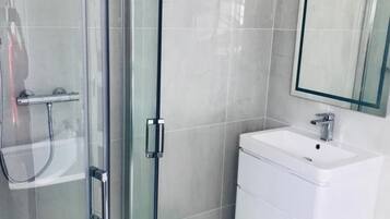 A modern bathroom with a glass shower enclosure, a white sink, and a mirror above the sink.