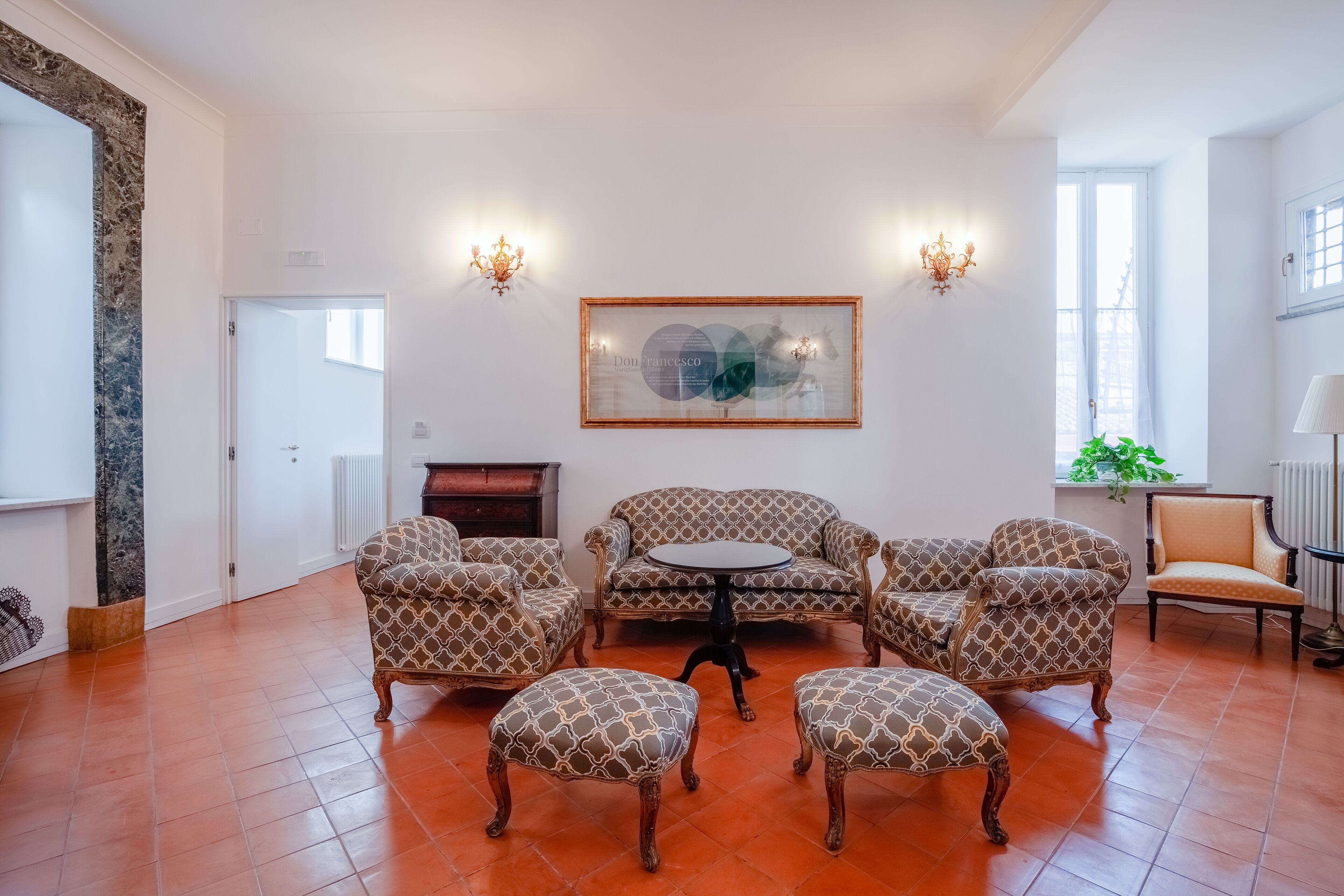A spacious living room with patterned sofas and ottomans arranged around a central table.