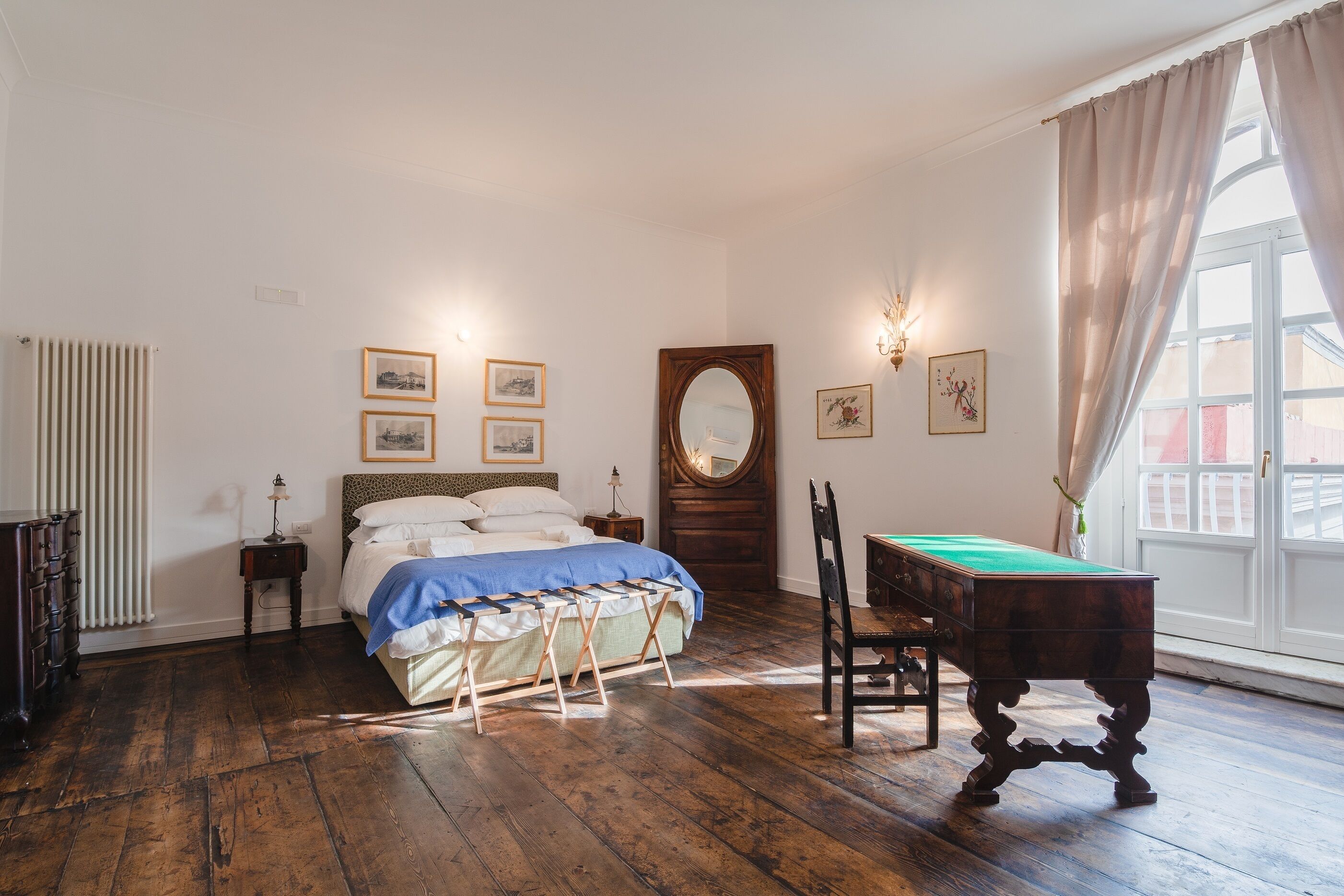 Une chambre à coucher avec un lit, une commode en bois, une table de billard et une grande fenêtre avec des rideaux.
