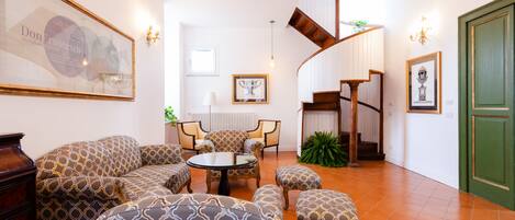 A living room with patterned sofas, a round coffee table, and a staircase leading to an upper level.
