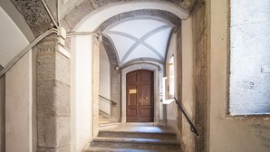 A stone staircase leading to a wooden door with a glass ceiling above. - Palazzo Marigliano (Naples)