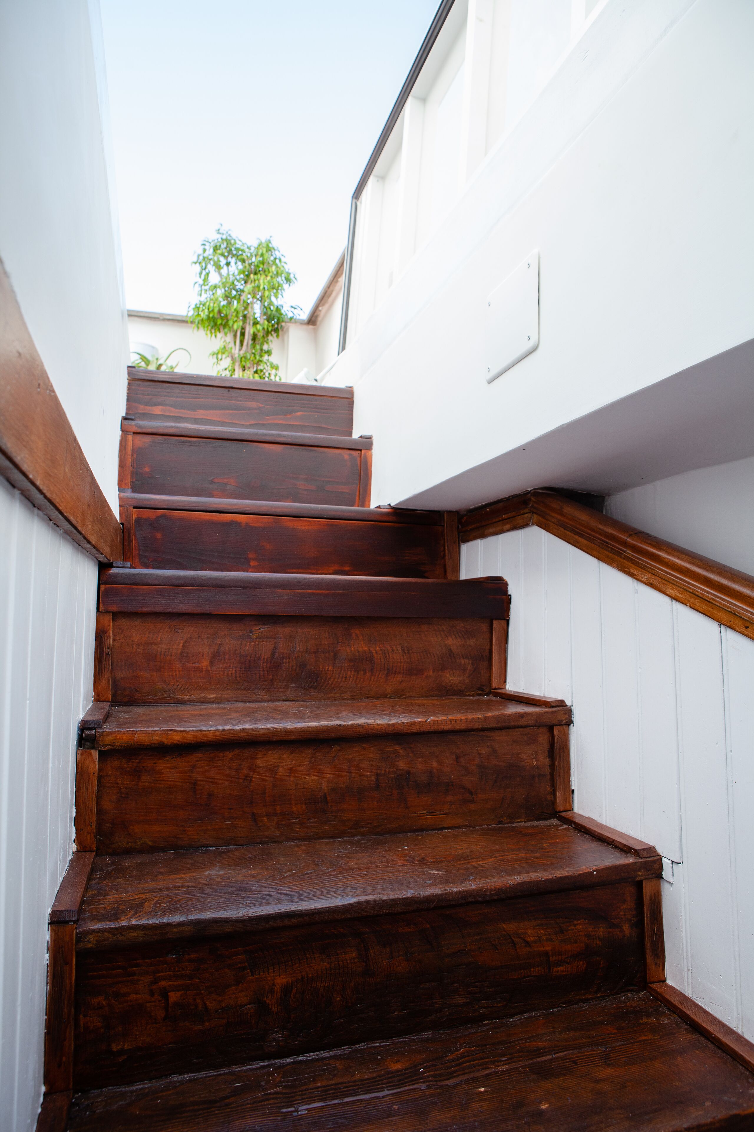 Eine Holztreppe mit weißen Wänden und einem Metallgeländer.