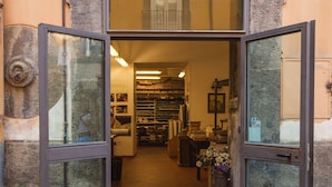 An entrance with a stone archway leading into a building with shelves of books and papers. - Palazzo Marigliano (Naples)
