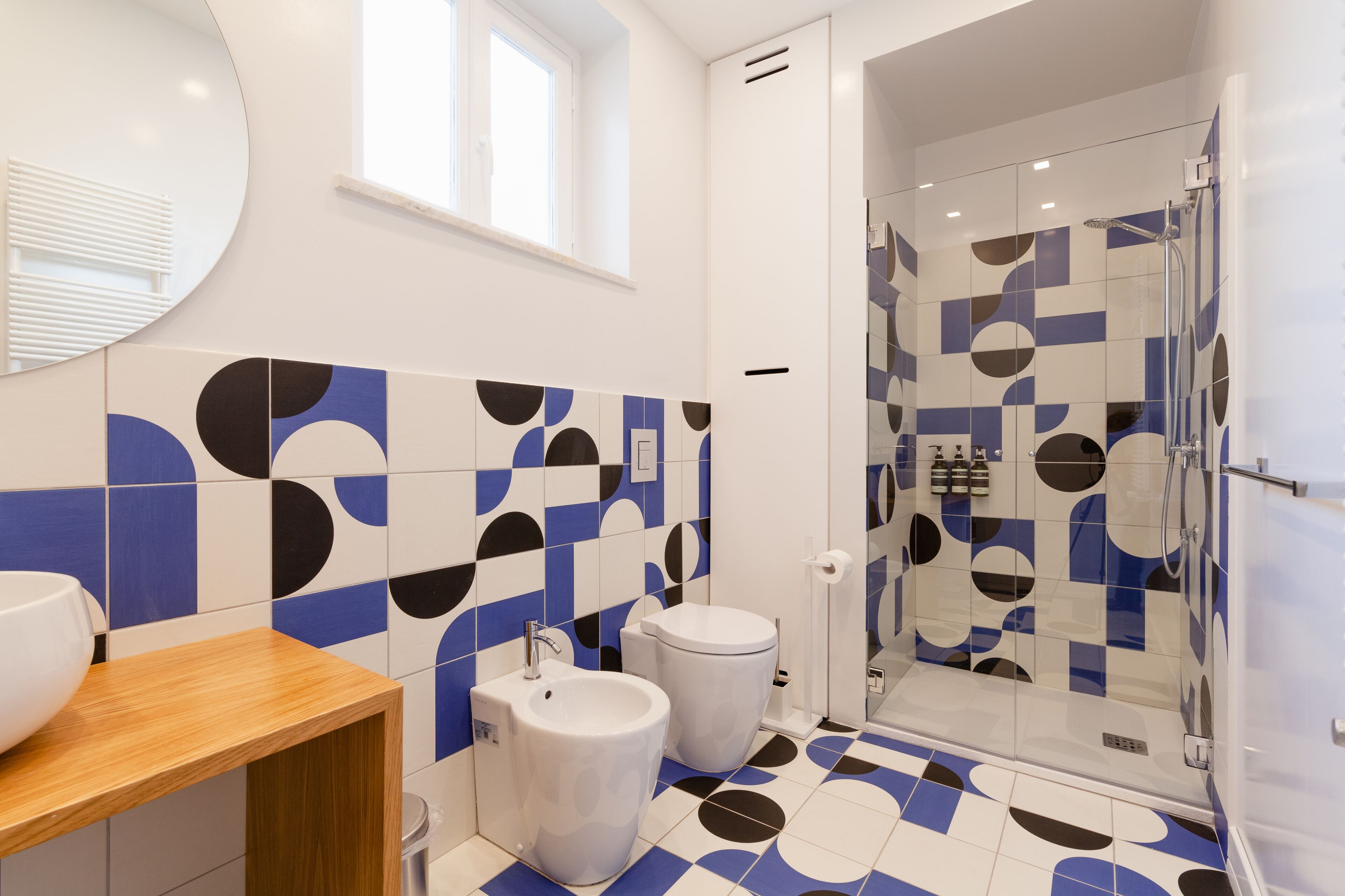 Un bagno moderno con uno specchio grande, un lavandino, un bidet e una zona doccia.