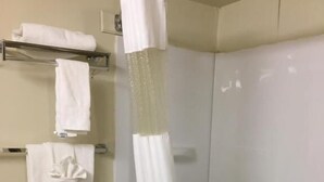 Un baño con bañera, cortina de ducha y toallero con toallas dobladas.