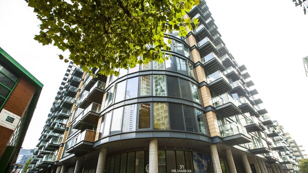 A modern building with a curved facade, large windows, and a sign indicating '31 Mill Harbour'.