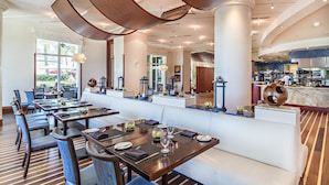 Un restaurante moderno con una barra central, varias mesas para comer y vistas al área exterior.
