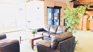 A lobby with a brown leather sofa, a wooden coffee table, and a potted plant. - Hotel Northern Star (Slave Lake)
