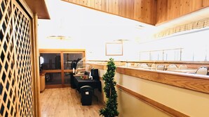 A reception area with a wooden counter, a small potted plant, and a seating area with a table and chairs. - Hotel Northern Star (Slave Lake)