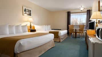 Two single beds with white linens and a bed runner, a desk with a TV and lamp, and a chair for dining.