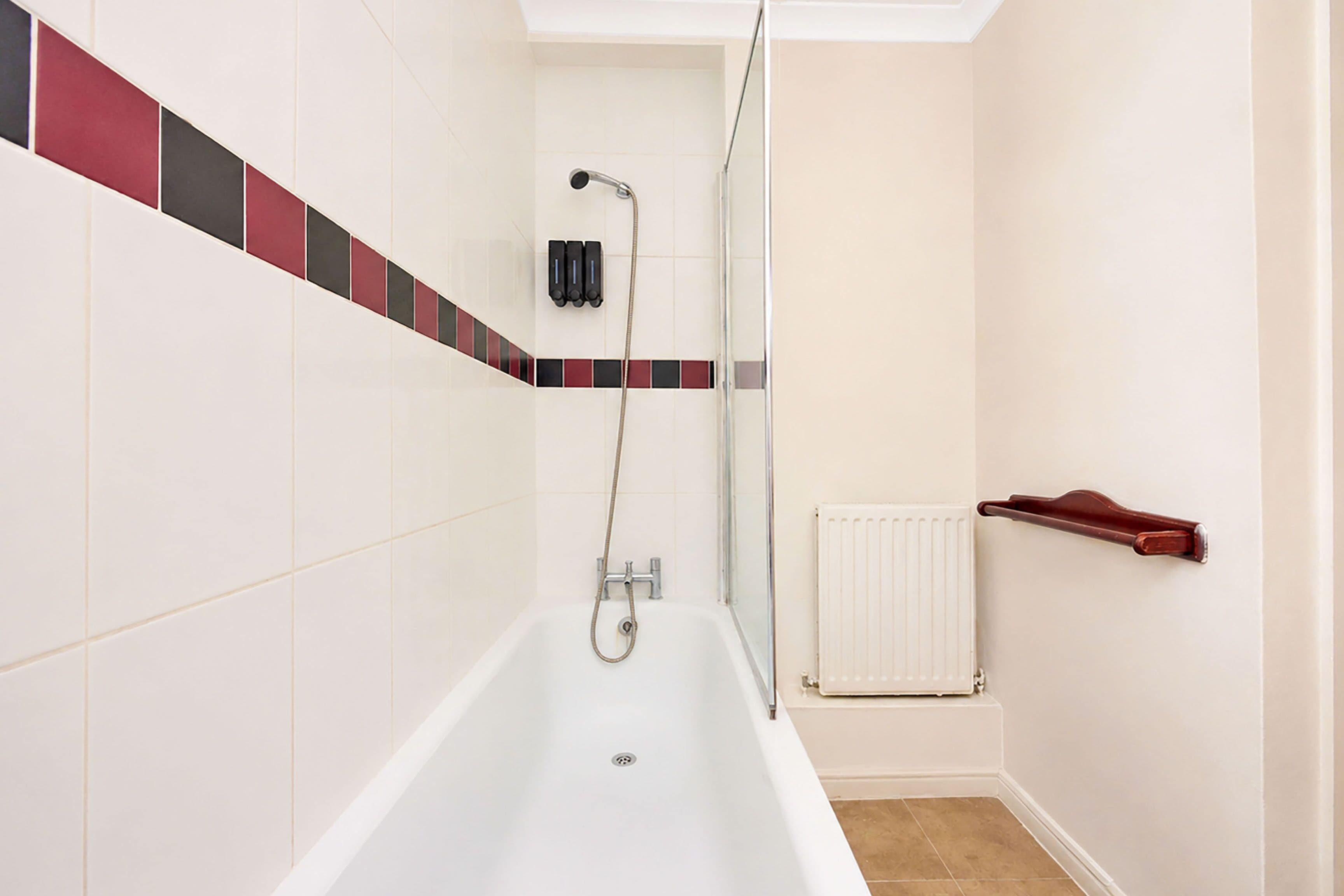 Une salle de bain avec une baignoire, une douche et un porte-serviettes.