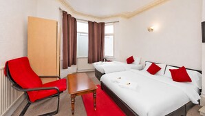 A hotel room with a bed, two bedside tables, a chair, a wardrobe, and a window with curtains. - Saji Hotel Ilford (Ilford)