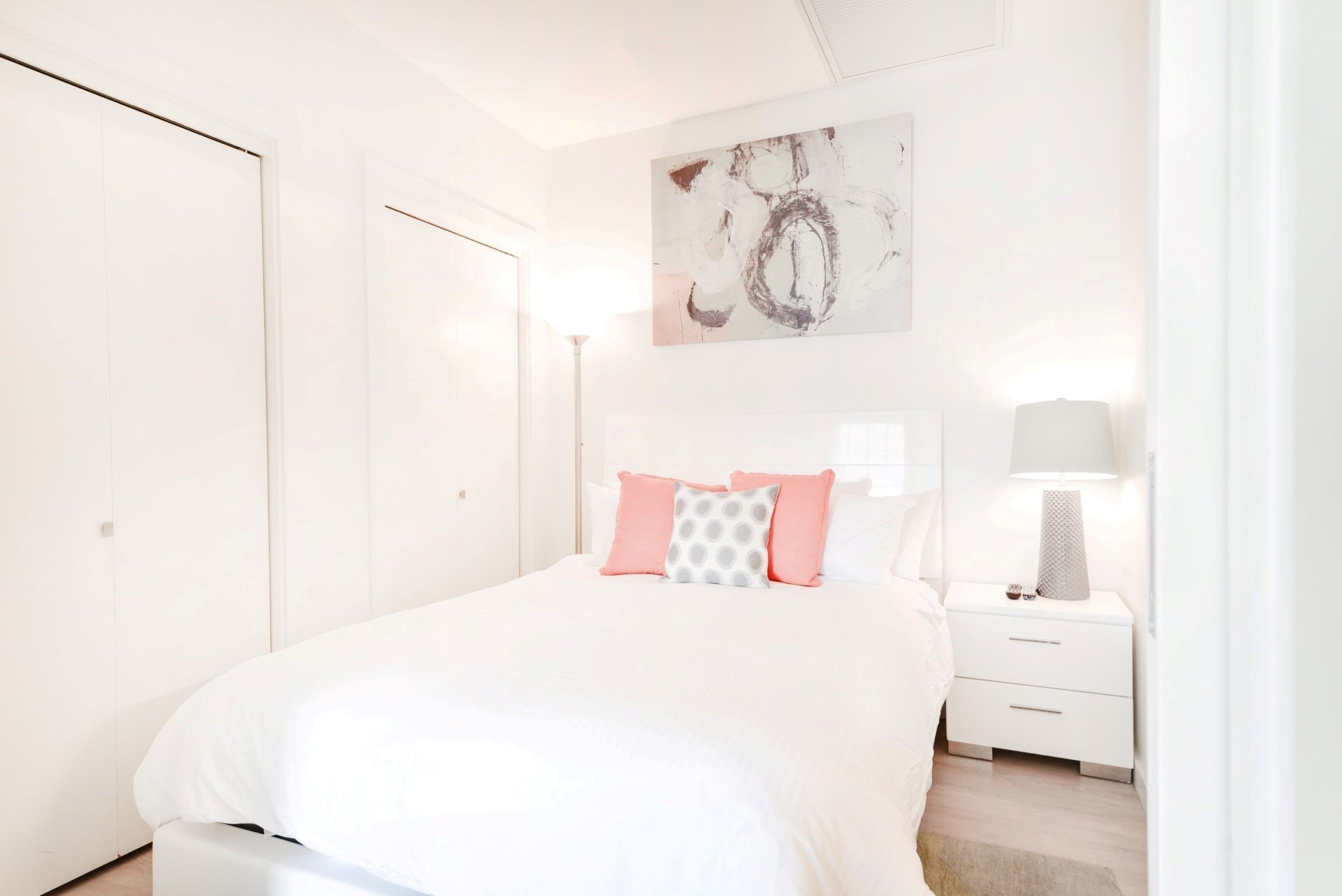 A bedroom with a bed, a nightstand, a lamp, and a painting on the wall.