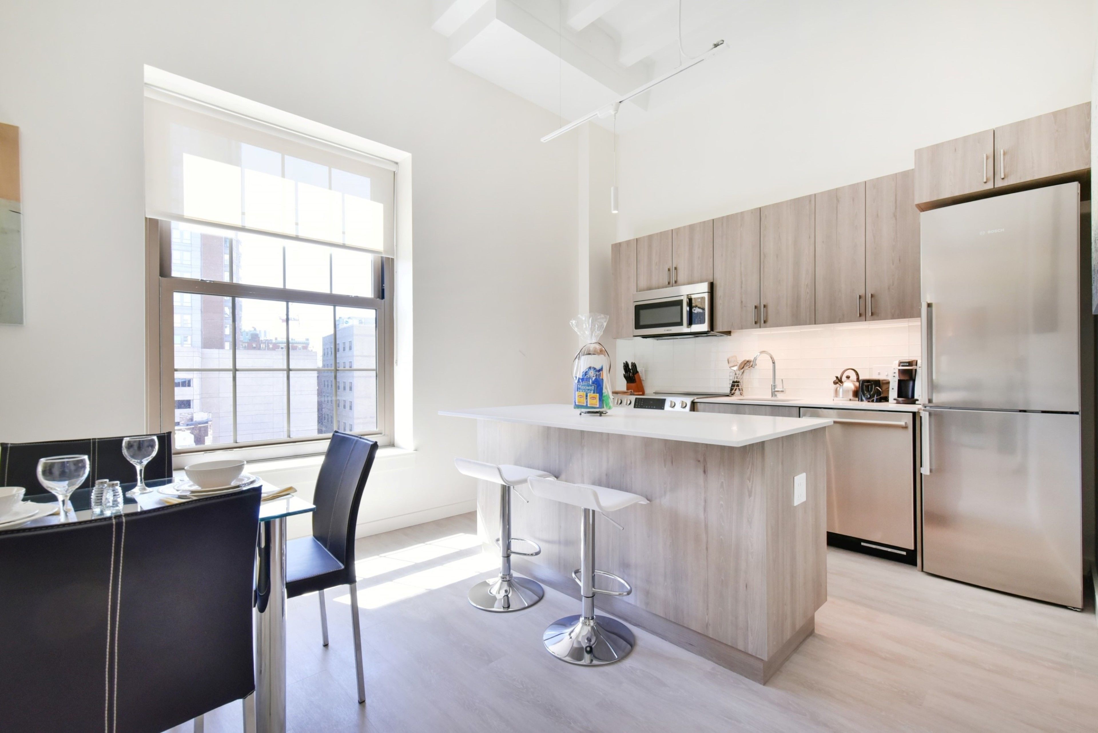 A modern kitchen with a central island, stainless steel appliances, and a dining area with a table and chairs.