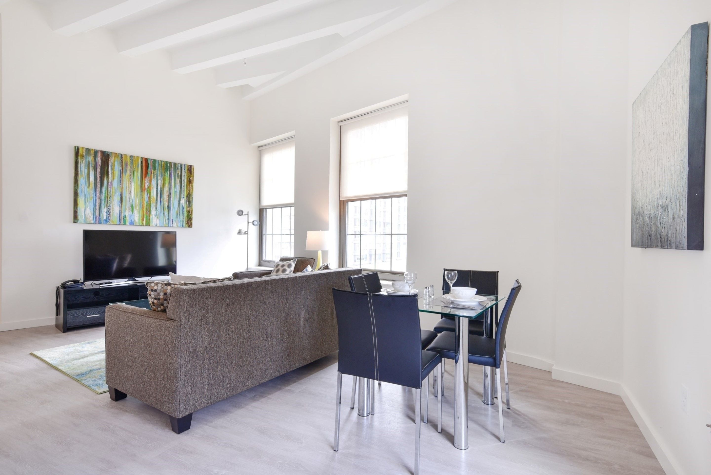Una sala moderna con un sofá, una mesa de comedor, sillas y un televisor.