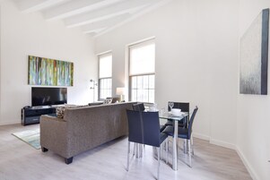 Een moderne woonkamer met een bank, eettafel, stoelen en een televisie.