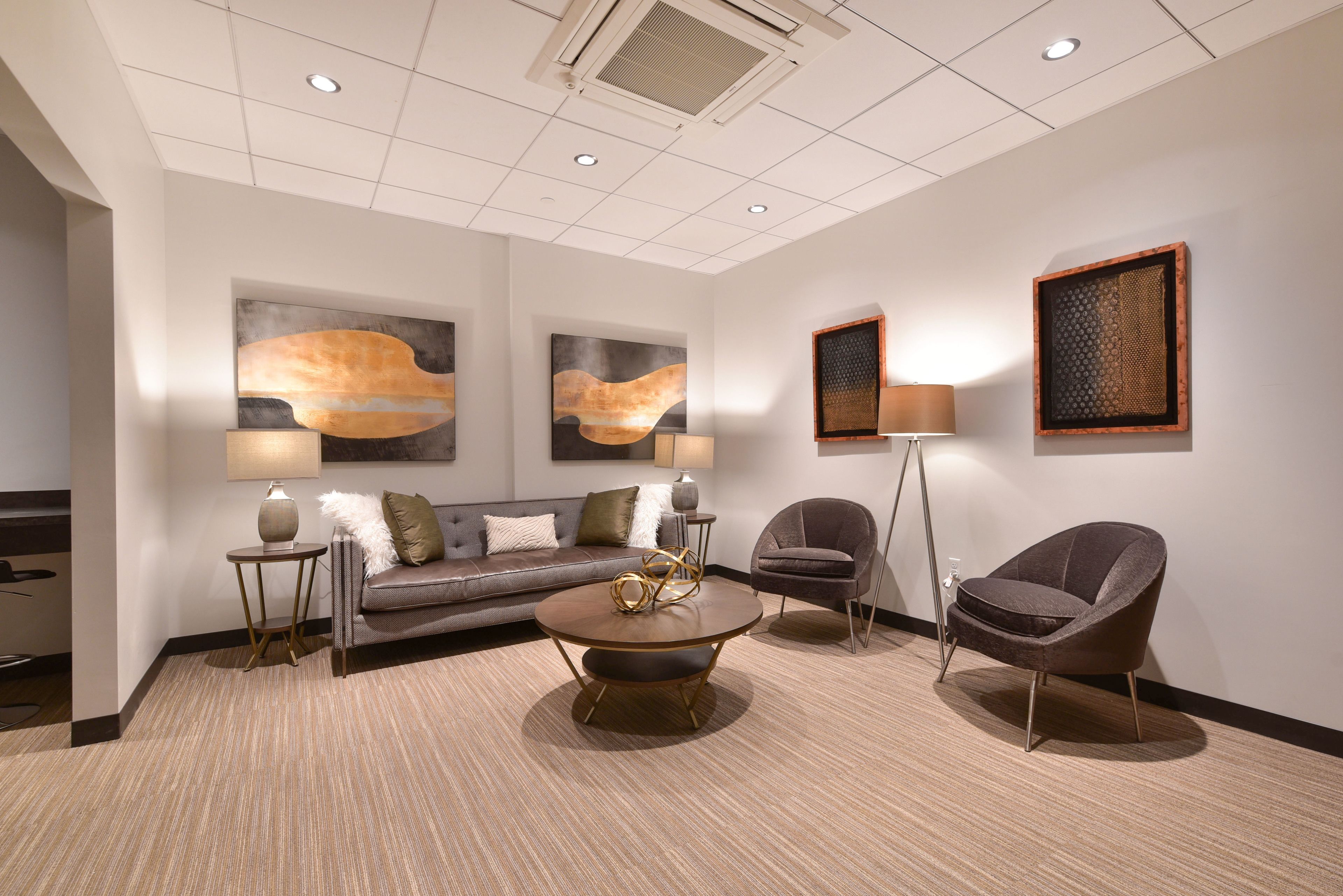 A modern lounge area with a sofa, two armchairs, a coffee table, and artwork on the walls.