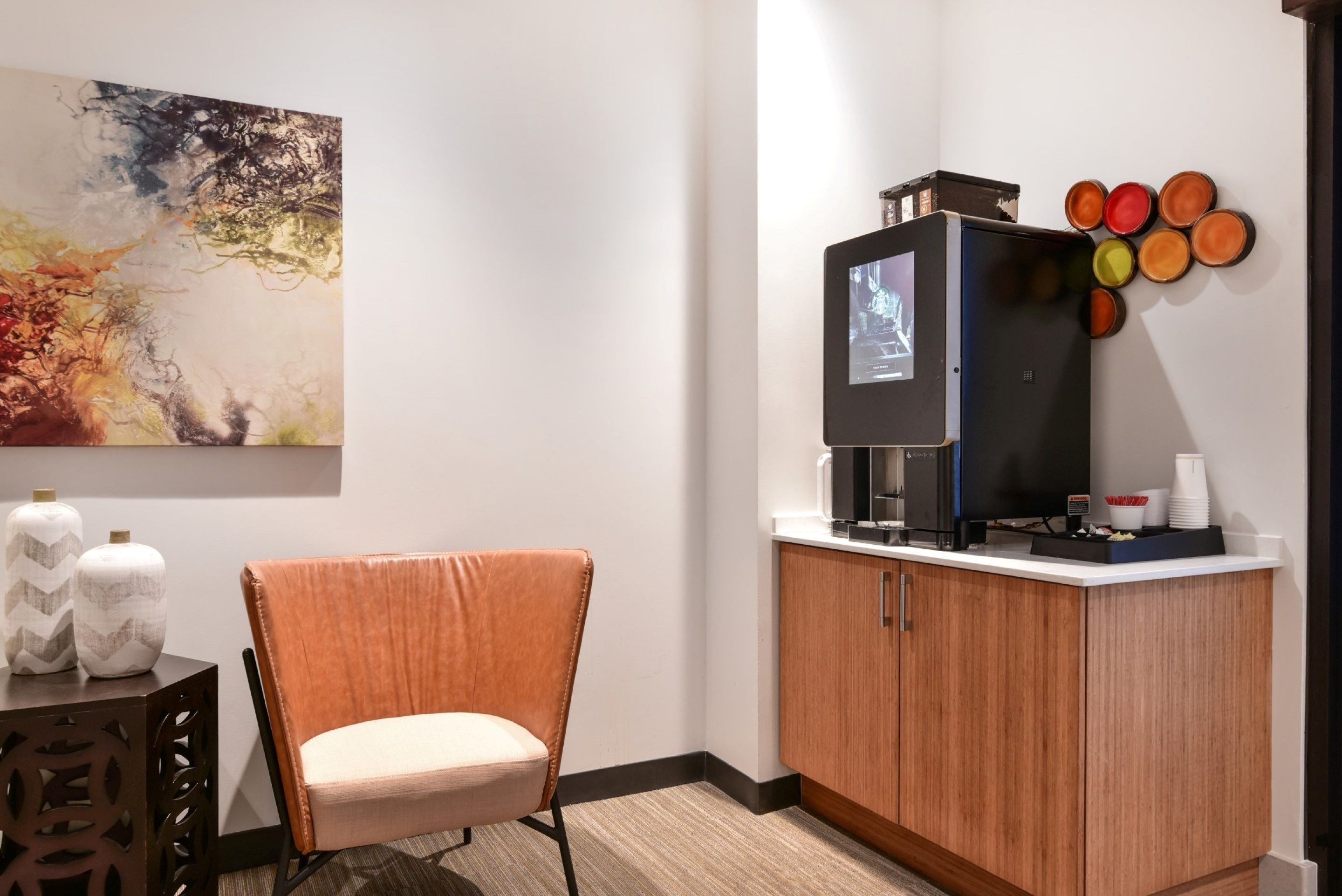 A modern room with a wooden cabinet, a television, and a wall art piece.