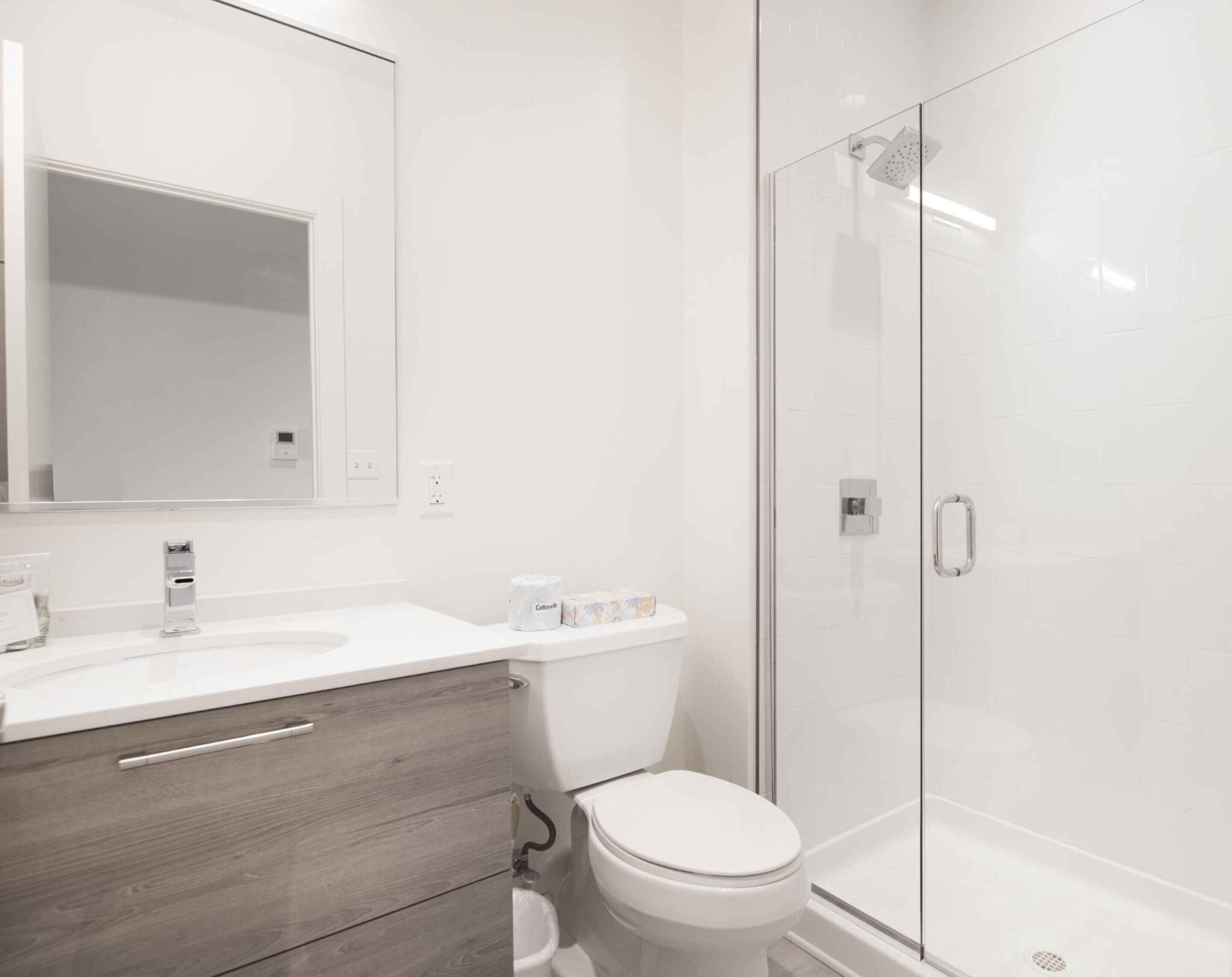 A modern bathroom with a white sink, a toilet, and a glass-enclosed shower.