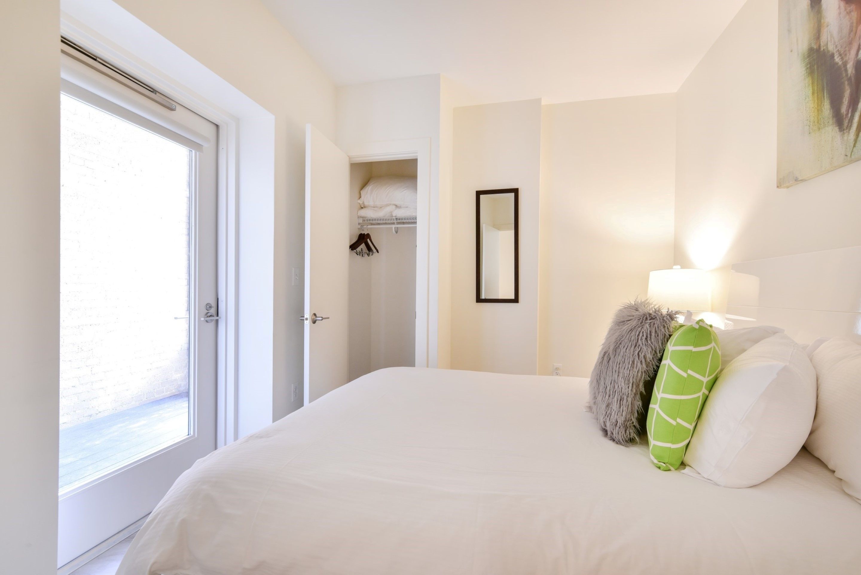 Un dormitorio con una cama grande, un armario, un espejo y una ventana.