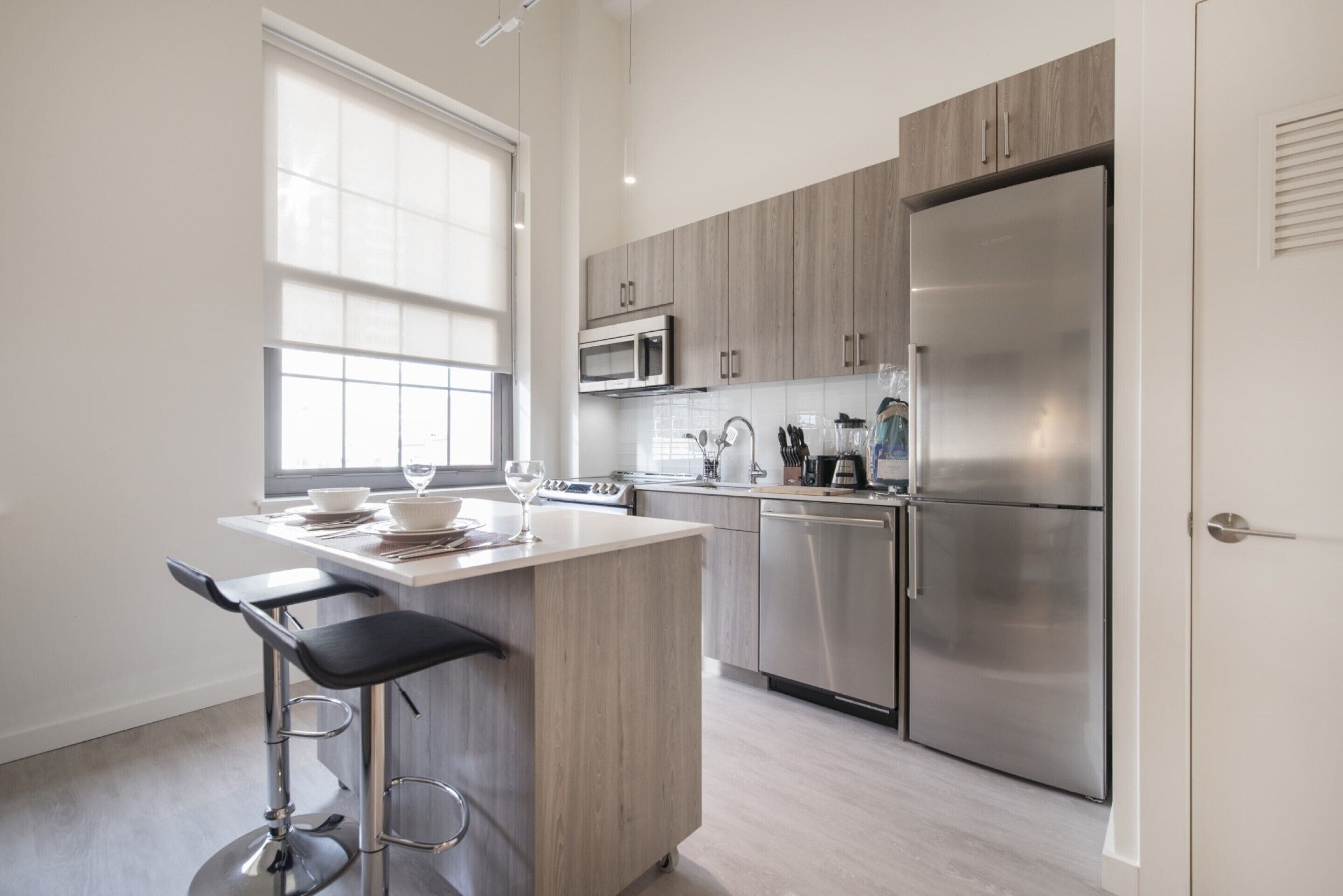 A modern kitchen with a central island, stainless steel appliances, and a window providing natural light.