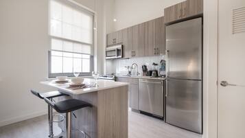 A modern kitchen with a central island, stainless steel appliances, and a window providing natural light.